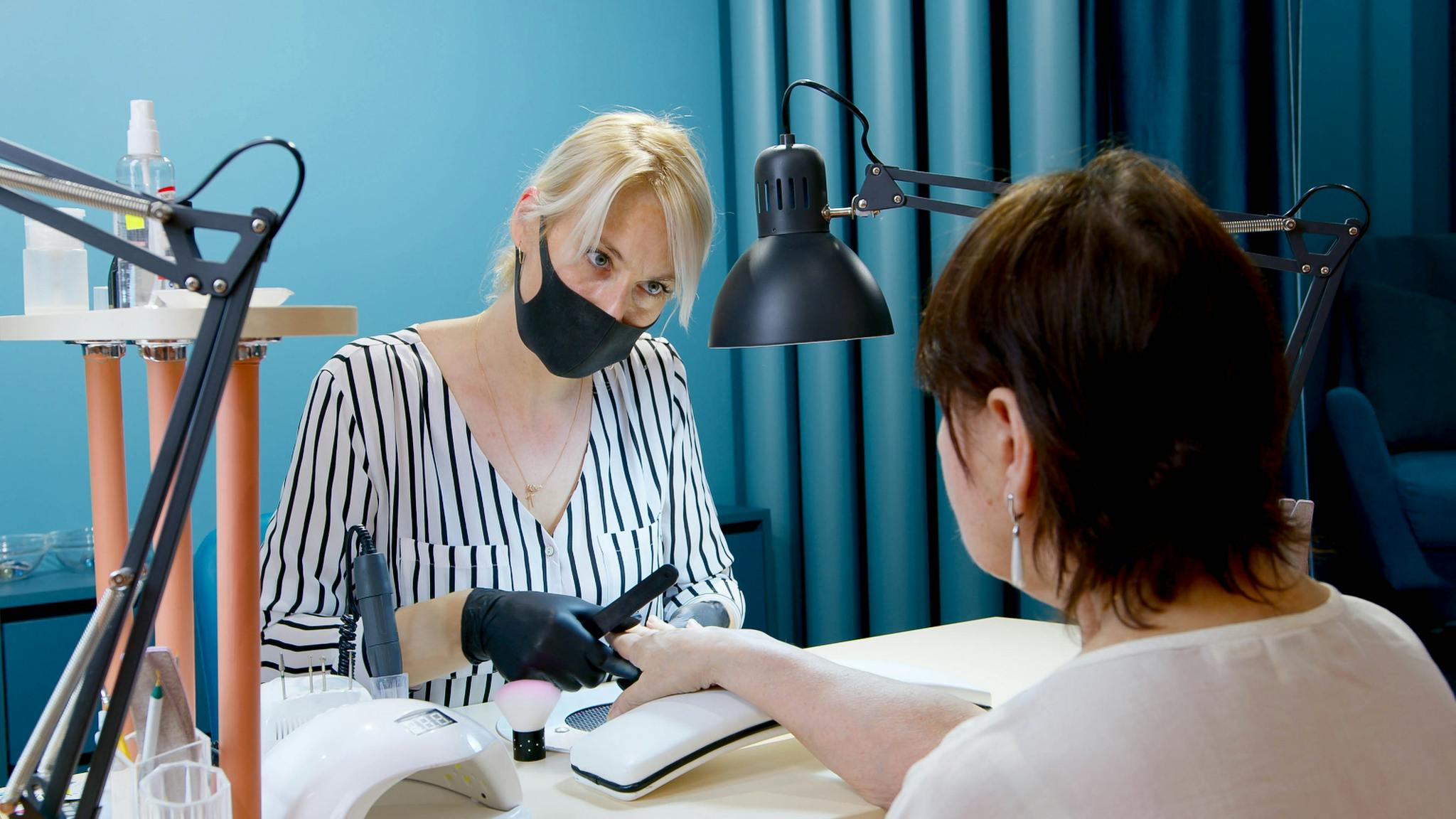 A manicurist professionally tending to a client’s nails in a modern salon.