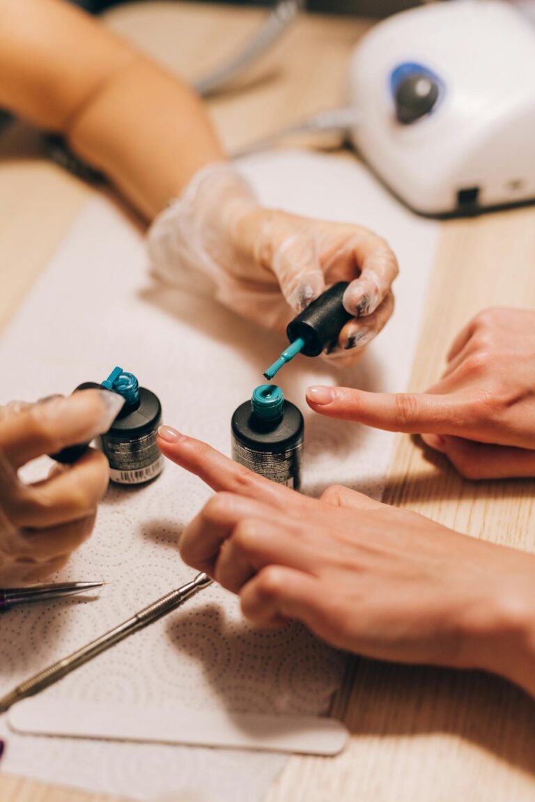 Close-up of a manicurist applying gel polish to a client's nails with precision.