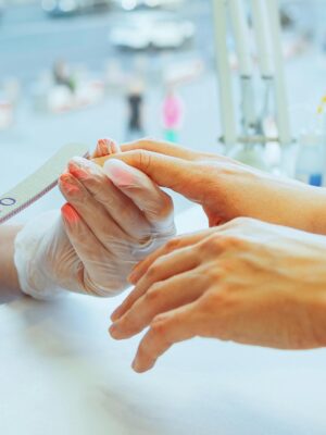 Close-up of a manicurist performing a nail file treatment on a customer's hand in a salon.