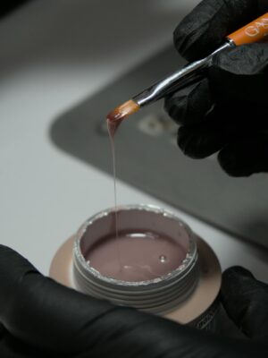 Detailed view of nail gel application with brush, showcasing beauty and care.